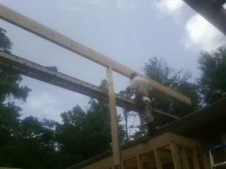 Carpenter setting a ridge beam over a new addition frame — Ice Dam Removal by Roofing Brothers in Beltsville