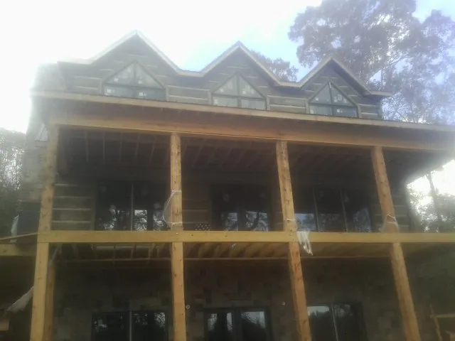 Dormers and porch framing on a large log home under construction — Roof Coating work by our crew in Beltsville