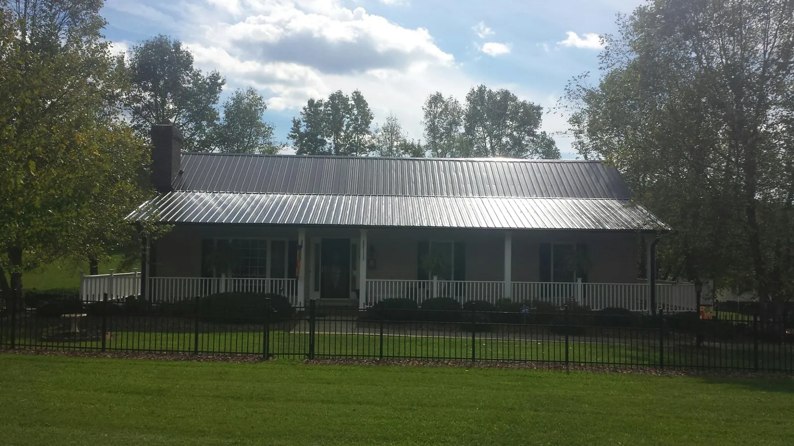 Gray metal roof on a brick ranch with a full width front porch — Gutter Guard Installation work by our crew in Beltsville