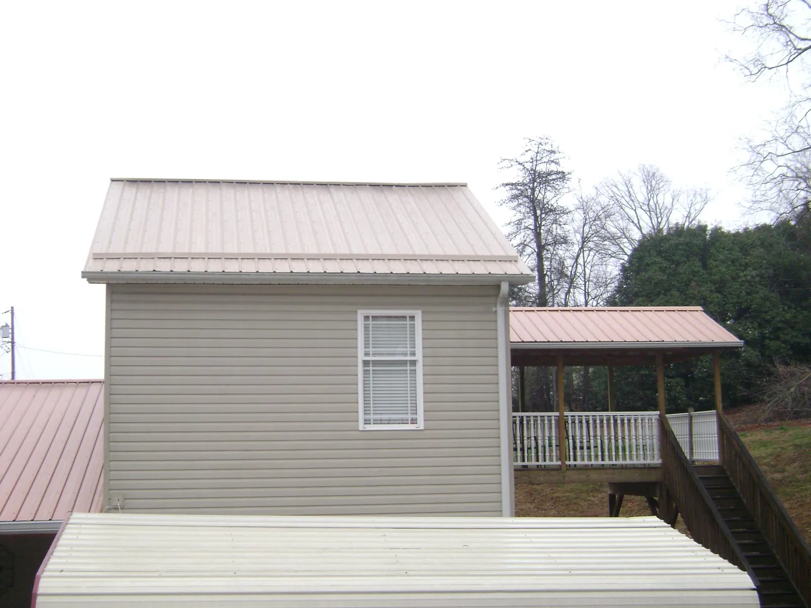 Tan metal roofs on a two story addition and attached porch, from a Roof Replacement job in Beltsville