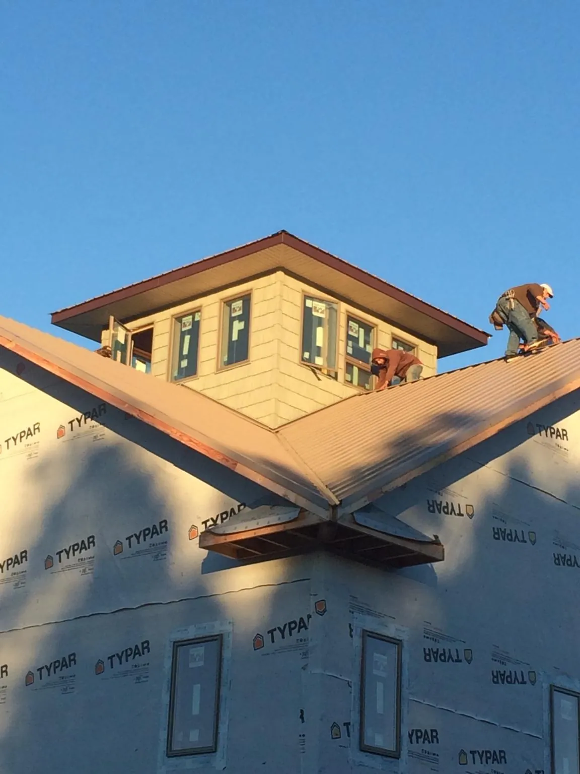 Roofers working around a rooftop cupola on a new metal roof at sunset — Roof Waterproofing in Beltsville by Roofing Brothers